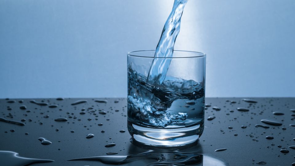 Clear water pouring into a glass — whole-home filtration improves taste at every tap